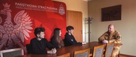 Uczniowie słuchają wykładów jednego z strażaków. Zdjęcie wykonane w salce konferencyjnej.