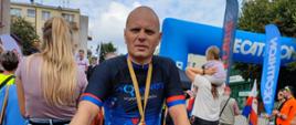 Zdjęcie przedstawia mł. asp. Jarosława Gacek stojącego przy rowerze, w tle ludzie, dekoracja zwycięzców wyścigu