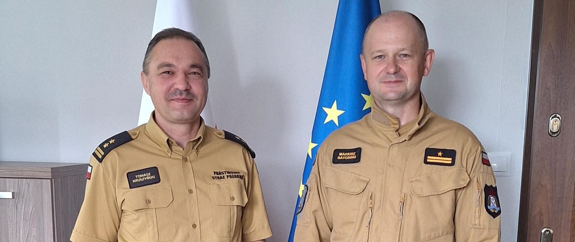 Zdjęcie przedstawia strażaków stojących w gabinecie komendanta podczas wręczenia awansu. 