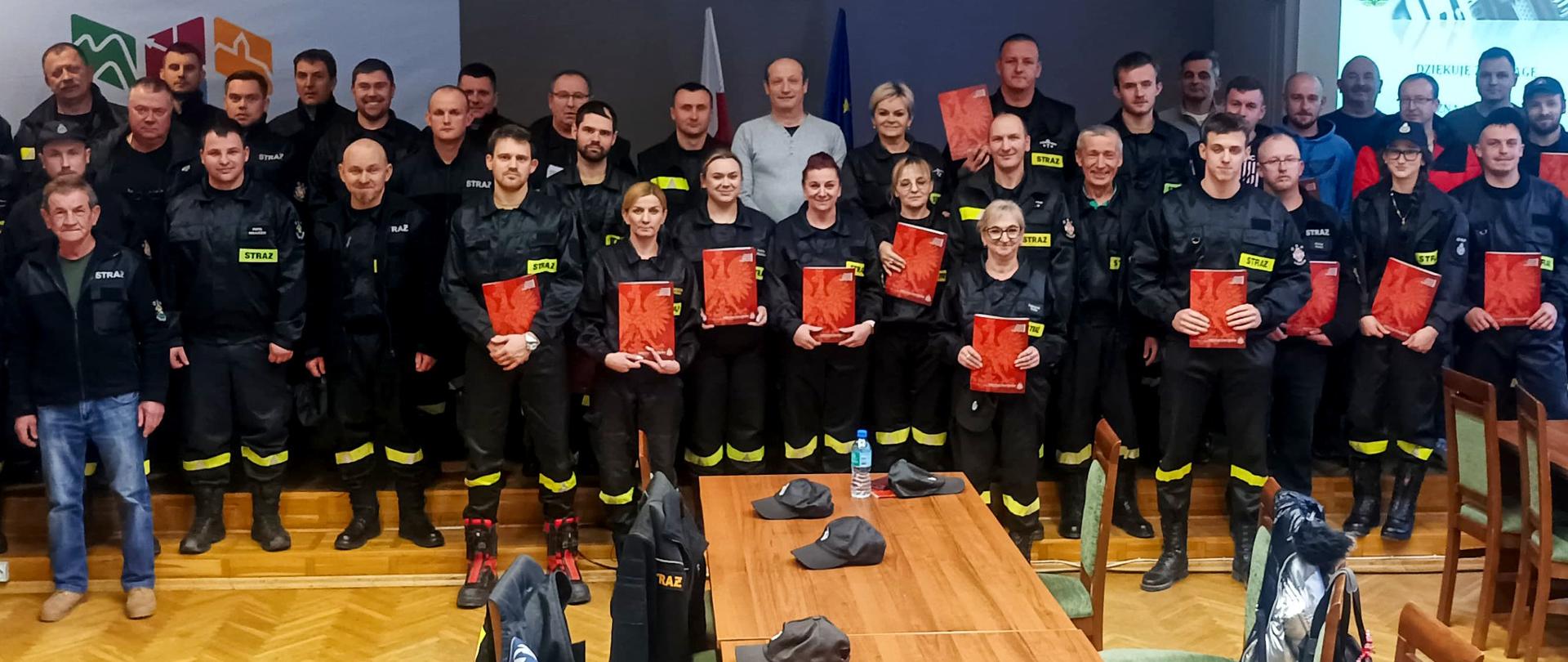 Zdjęcie przedstawia całą grupę strażaków OSP z dyplomami w rękach w sali urzędu.