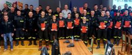 Zdjęcie przedstawia całą grupę strażaków OSP z dyplomami w rękach w sali urzędu.