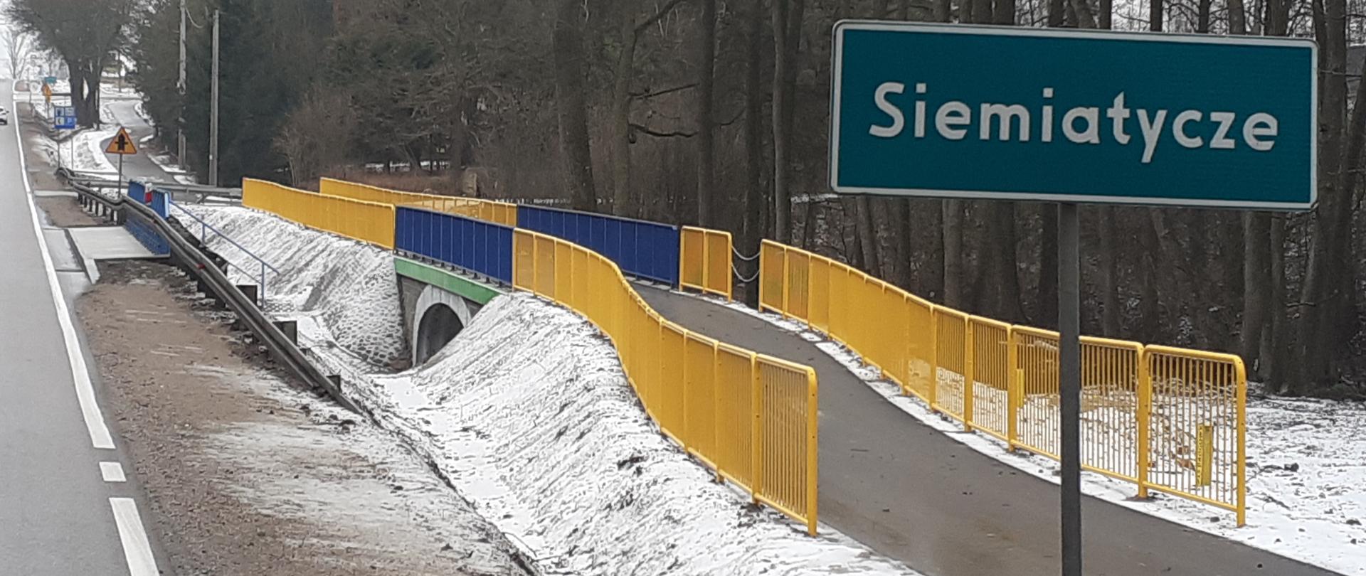 Ścieżka pieszo - rowerowa a obok niej stoi znak z nazwą miejscowości Siemiatycze