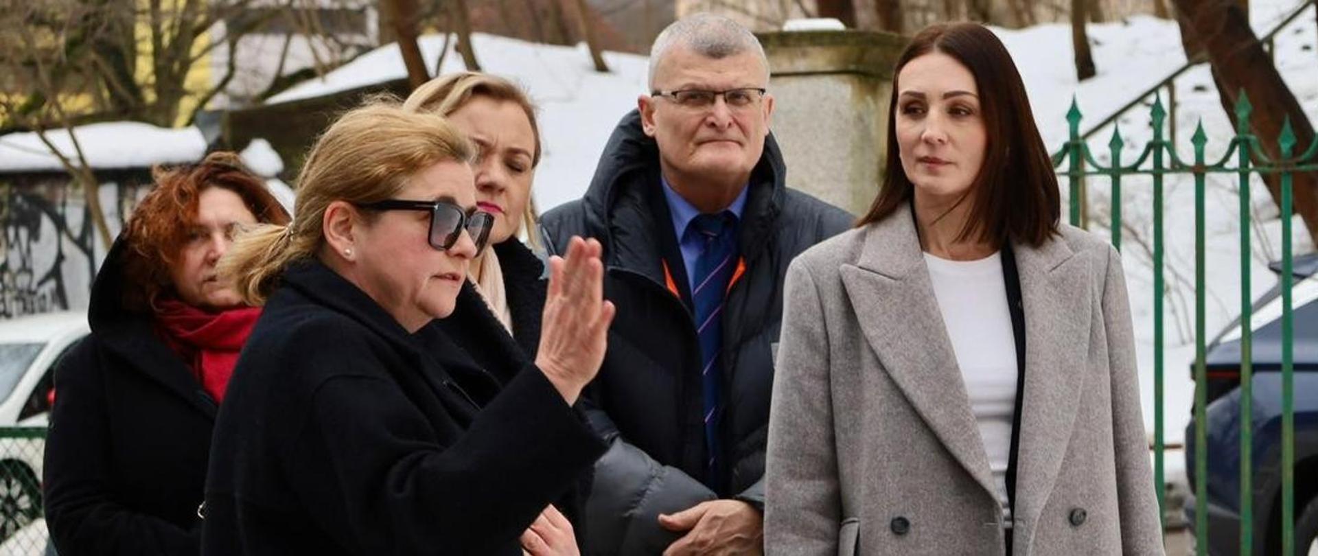 Kilka osób stoi przed budynkiem szpitala i rozmawia