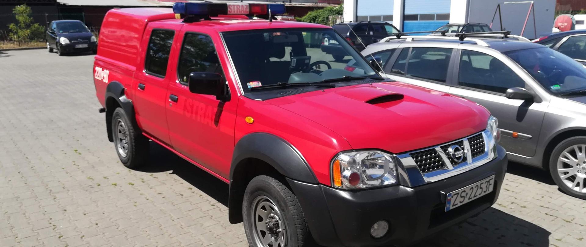 Czerwony samochód typu pickup z zamontowanym kogutem na dachu z napisem straż