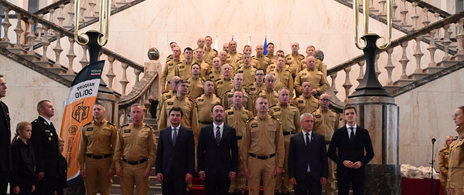 Grupowe zdjęcie funkcjonariuszy na schodach.