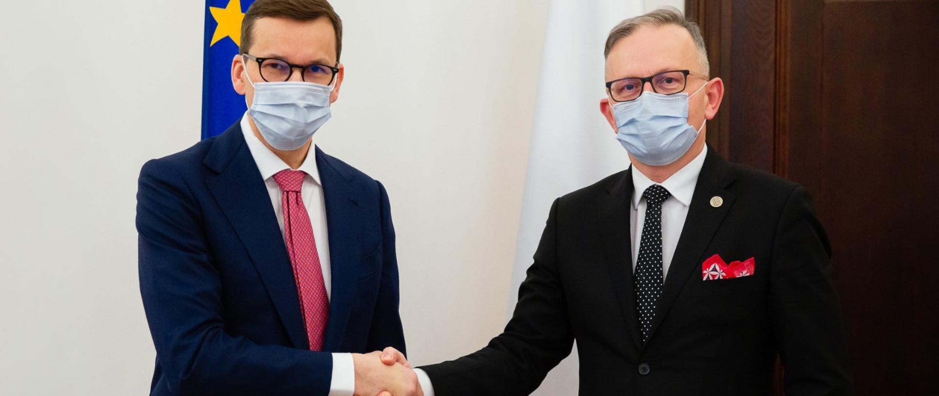 Uścisk dłoni, premier Mateusz Morawiecki i z-ca szefa KAS Mariusz Gojny.