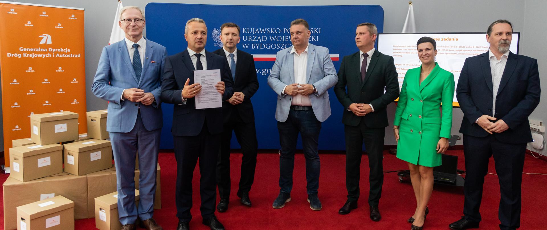 
Grupa mężczyzn w garniturach stojąca przed mikrofonem
