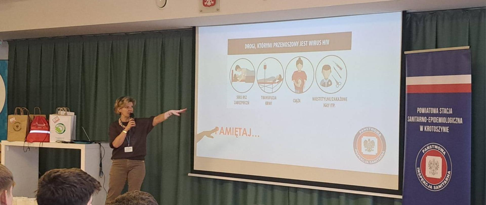 Światowy Dzień Aids w Krotoszynie 2025 - grafika przedstawia pracownice PSSE w Krotoszynie prowadzącą prezentacje na temat HIV/AIDS