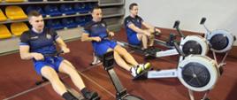 Strażacy na ergometrach wioślarskich.