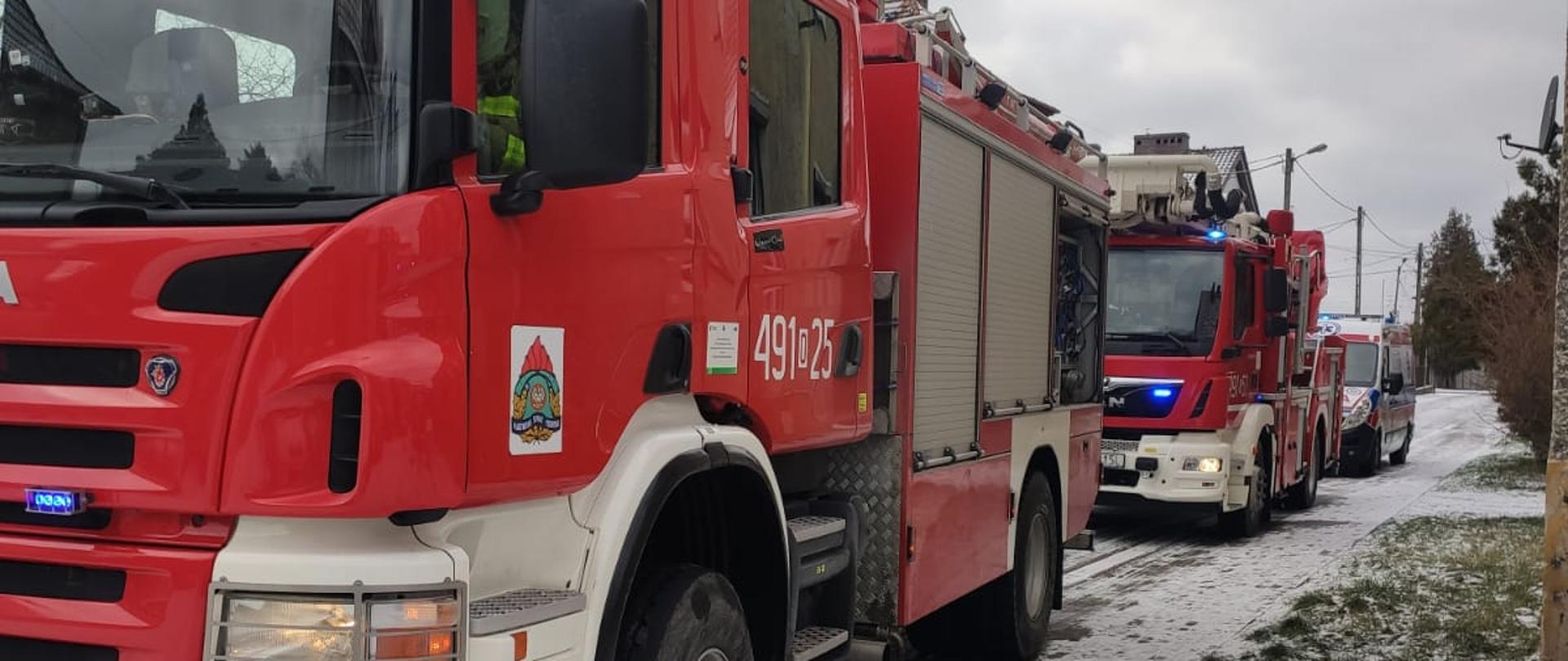 Na zdjęciu znajdują się dwa samochody strażackie stojące na drodze