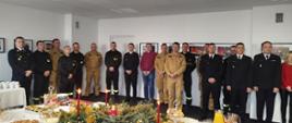 Na zdjęciu widoczni są: funkcjonariusze i pracownicy cywilni Komendy Powiatowej Państwowej Straży Pożarnej w Ostrowcu Świętokrzyski oraz Wiceprezes Zarządu Oddziału Wojewódzkiego Związku OSP RP, Wiceprezes Zarządu Oddziału Powiatowego Związku OSP RP, członkowie prezydium Zarządu Oddziału Powiatowego ZOSP RP oraz kapelan powiatowy strażaków podczas spotkania opłatkowego.
