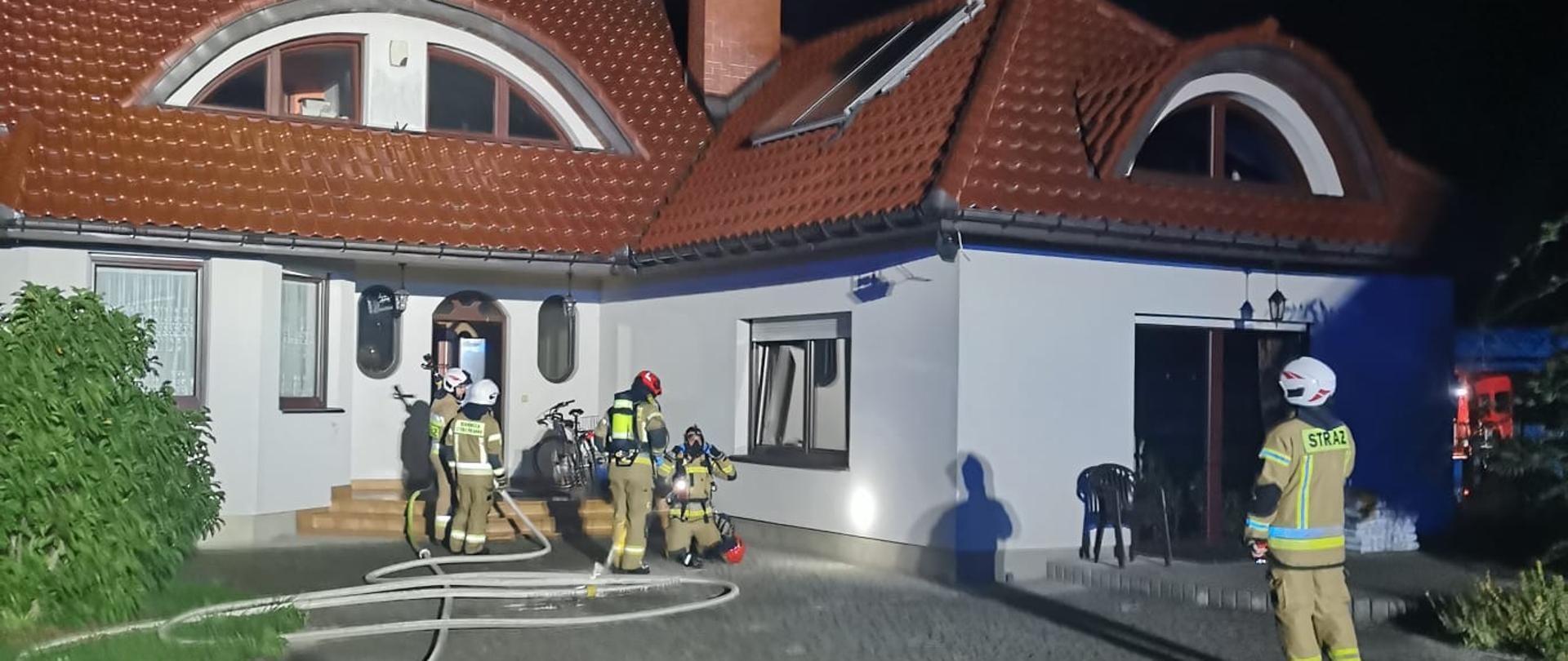 Na zdjęciu pracujący strażacy podczas gaszenia pożaru poddasza. 