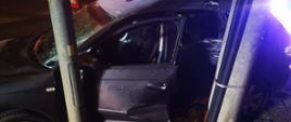 Uszkodzony samochód osobowy od strony kierowcy znajduje się przy słupie