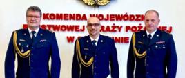 Zdjęcie przedstawia stojących na tle loga PSP Zachodniopomorskiego Komendanta Wojewódzkiego st. bryg. Jarosława Tomczyka, Komendanta Powiatowego PSP w Gryfinie bryg. Sławomira Michalskiego i Zastępce Komendanta Powiatowego Państwowej Straży Pożarnej w Gryfinie bryg. Piotra Juzyszyna.