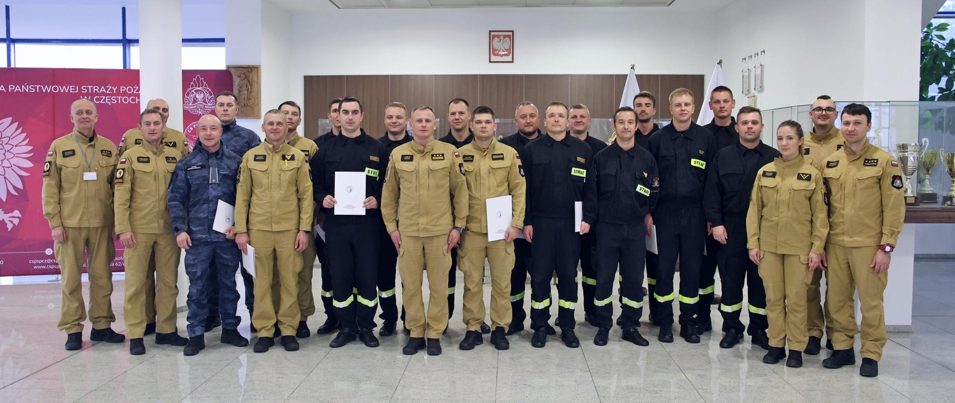 Pamiątkowe zdjęcie funkcjonariuszy PSP oraz Straży Marszałkowskiej będących uczestnikami szkolenia w zakresie ratownictwa chemicznego i ekologicznego (18 osób) w towarzystwie Zastępcy Komendanta Centralnej Szkoły PSP, funkcjonariuszki CS PSP oraz czterech funkcjonariuszy CS PSP