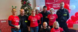 Strażacy i wolontariusze w koszulkach z napisem "Szlachetna Paczka" pozują do zdjęcia