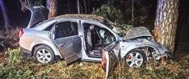Samochód osobowy po uderzeniu w drzewo przodem. Zdjęcie wykonane w porze nocnej.