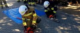 Strażacy odpalający pilarki do drewna podczas ćwiczeń