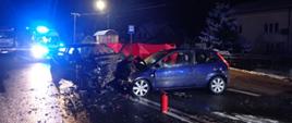 Śmiertelny wypadek w Parszowie. Noc. Na pierwszym planie dwa rozbite samochody biorące udział w wypadku. Za nimi widoczny parawan oraz samochód pogotowia z widocznymi sygnałami świetlnymi.
