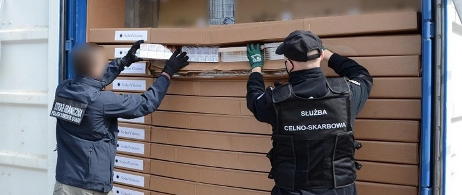 Funkcjonariusz KAS i SG wyjmują nielegalne papierosy z kontenera