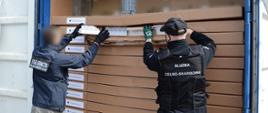 Funkcjonariusz KAS i SG wyjmują nielegalne papierosy z kontenera