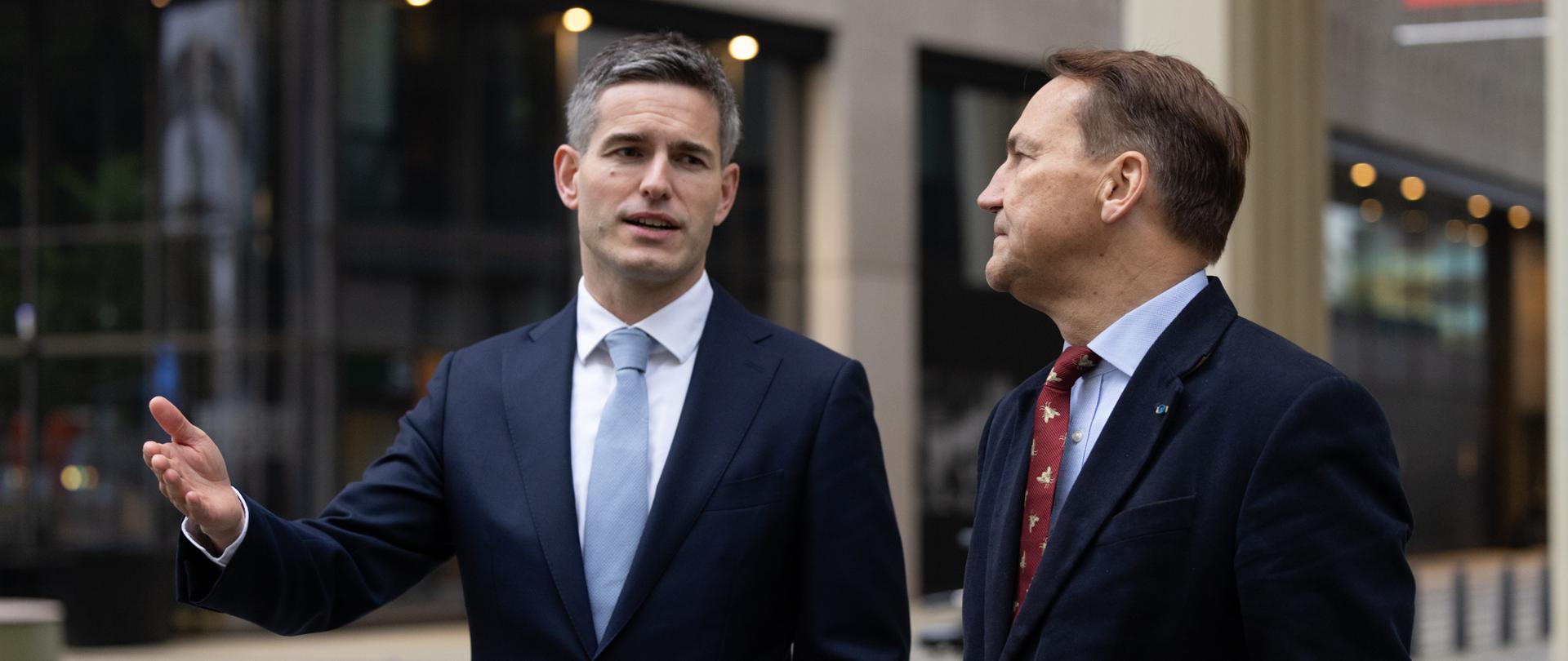 Wicepremier Sikorski z ministrem spraw zagranicznych Niderlandów Tomem Berendsenem na ulicy Hagi, w trakcie rozmowy. Ministrowie są w trakcie rozmowy i gestykulują.
