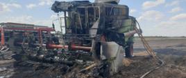 pożary podczas żniw. na zdjęciu widać stojący na polu spalony kombajn, w tle samochód pożarniczy i pola