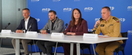 Prezes targów poznańskich, wiceprezydent Poznania, wicewojewoda wielkopolska oraz zastępca komendanta wojewódzkiego siedzą za stołem, informując do mikrofonów przedstawicieli mediów o nadchodzących targach. W tle ścianka reklamowa.