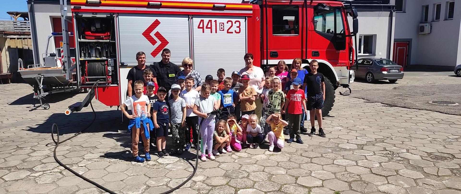 Na zdjęciu widać grupę dzieci z nauczycielkami i strażakami przed wozem bojowym
