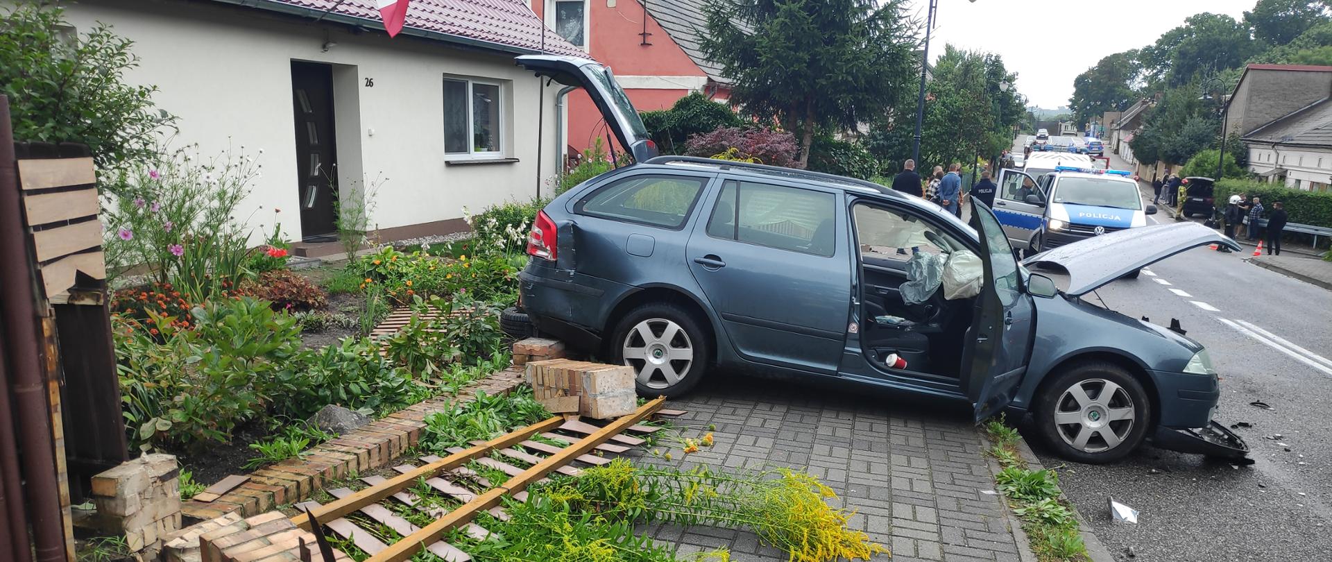 Na zdjęciu widoczne jest auto osobowe marki Scoda, które uległo wypadkowi. Na pierwszym planie zniszczone ogrodzenie posesji