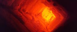 Zdjęcie przedstawia wnętrze komina, w którym powstał pożar. Przewód kominowy jest oblepiony grubą warstwą sadzy rozgrzaną do bardzo wysokiej temperatury. Komin przybiera kolory od żółtego do czerwonego na skutek bardzo wysokiej temperatury.