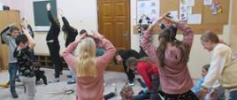 Zdjęcie z warsztatów muzyczno-ruchowych dla uczniów klas I, II, III cyklu 6 letniego - 13.01.2023. Na zdjęciu grupa bawiących się dzieci.