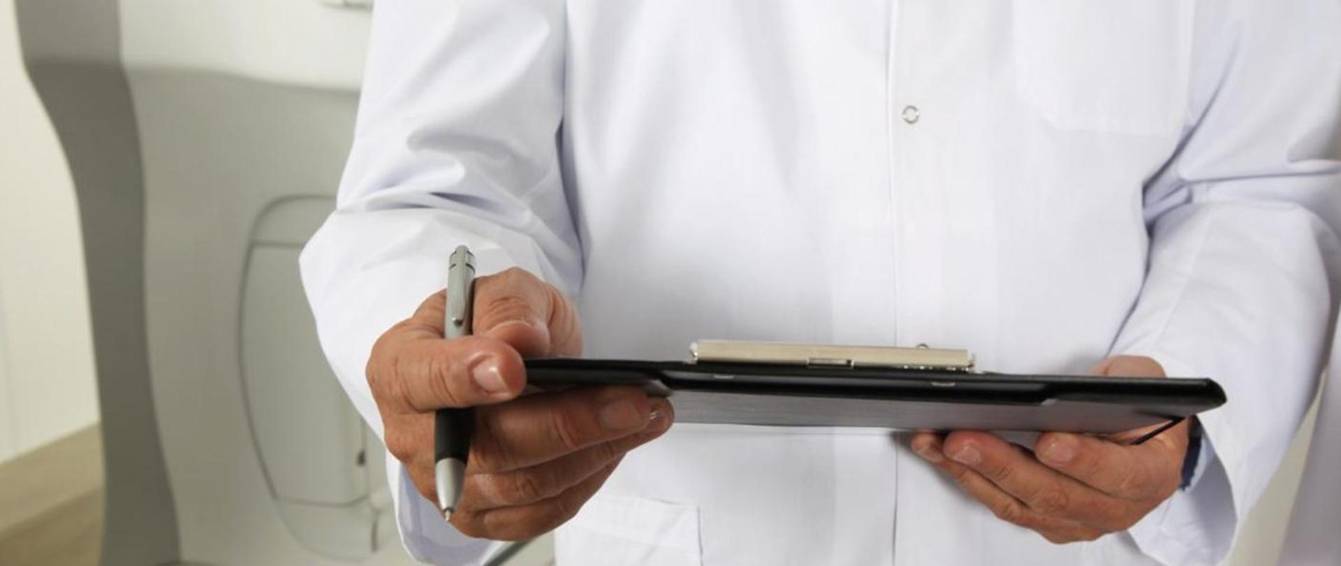Dłonie lekarza trzymające teczkę i długopis