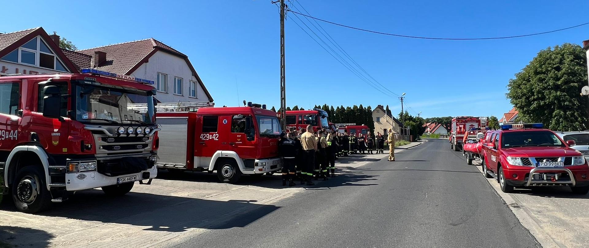 Na zdjęciu widać samochody pożarnicze oraz strażaków w miejscu koncentracji przy remizie OSP Łubowo. Dowódca zabezpieczenia omawia plan zabezpieczenia
