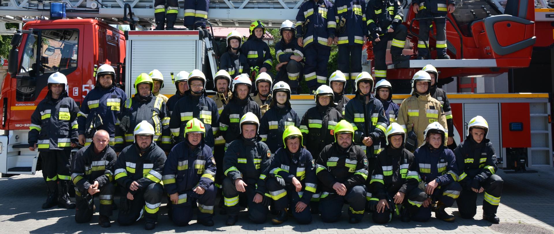 Zdjęcie grupowe strażaków, którzy ukończyli szkolenie na tle drabiny pożarniczej