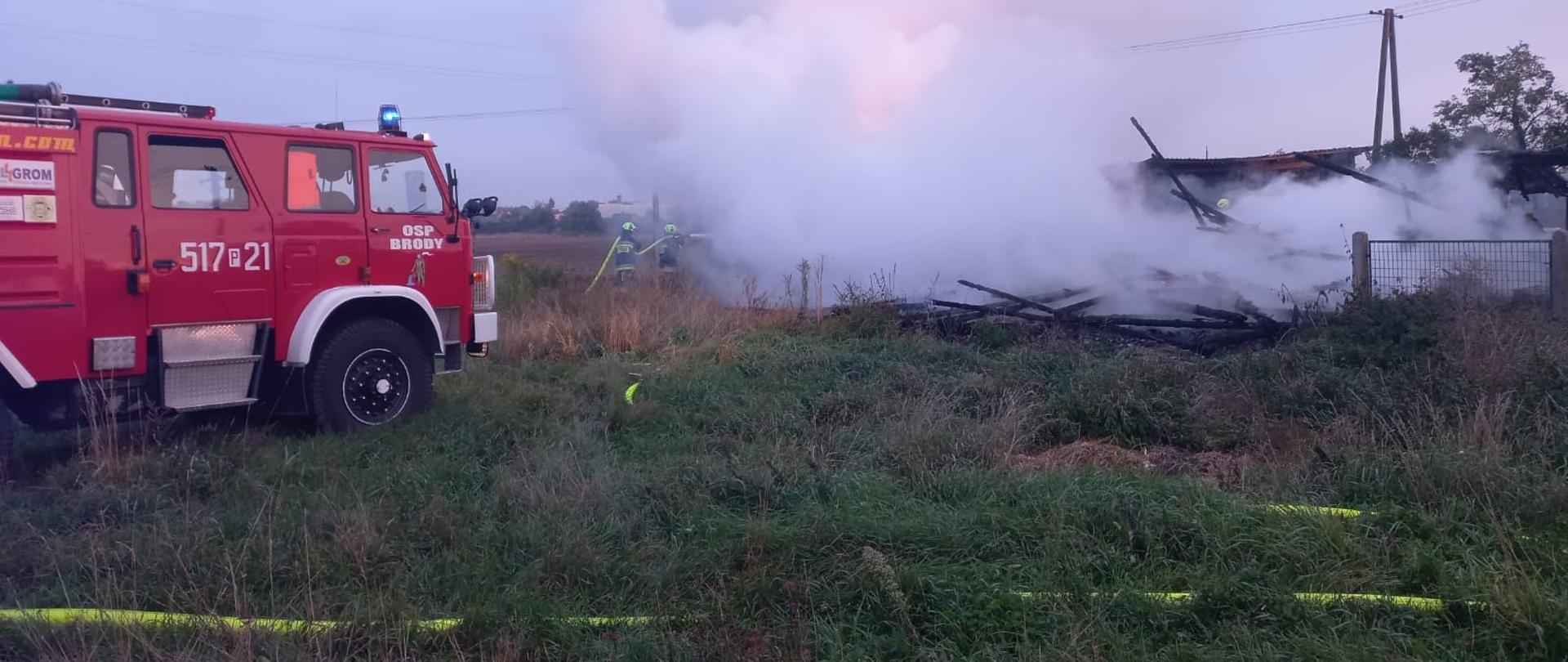 Samochód gaśniczy OSP Brody, na dalszym planie strażacy gaszący stodołę.
