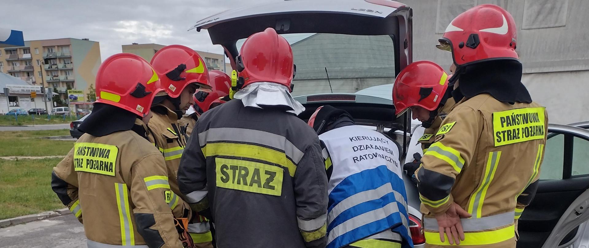 Strażacy zakręcający zawór LPG w samochodzie osobowym na parkingu. 