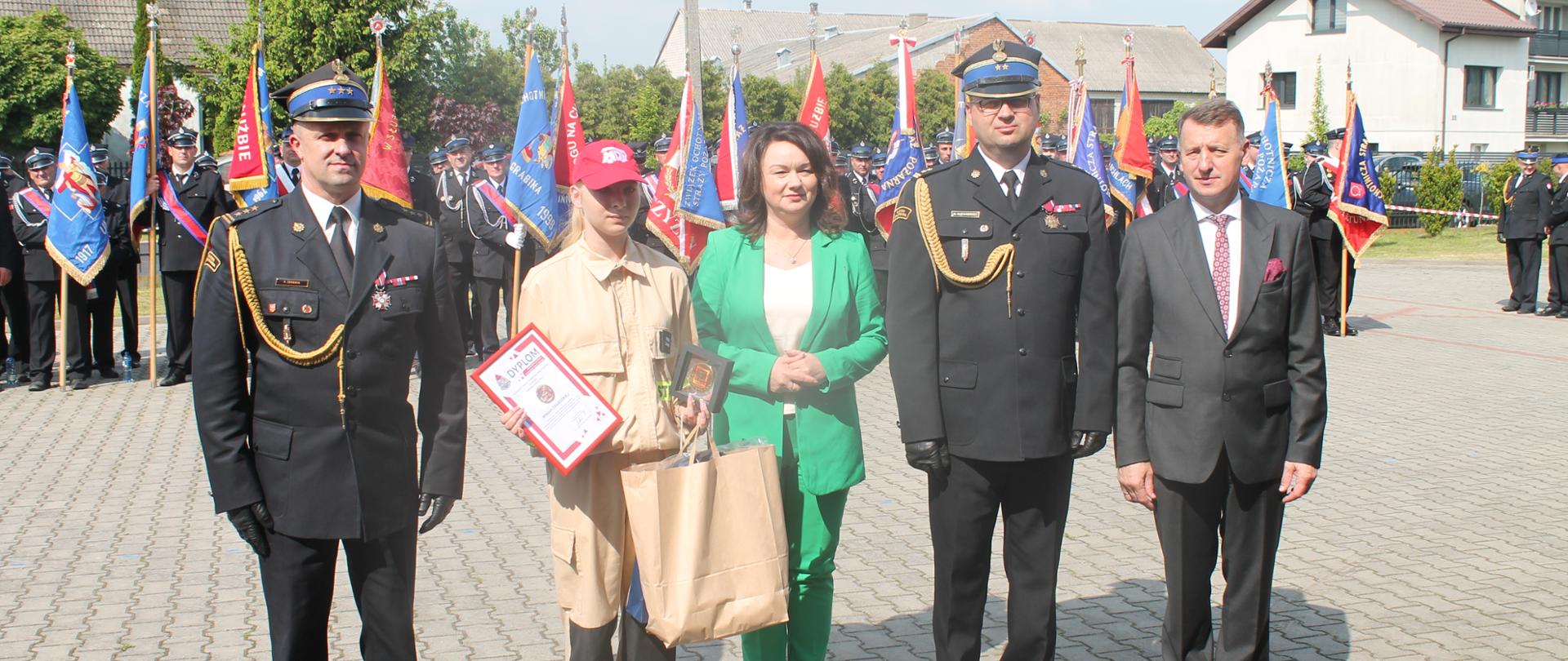 Zdjęcie przedstawia druhnę i osoby wręczające jej nagrodę i odznakę