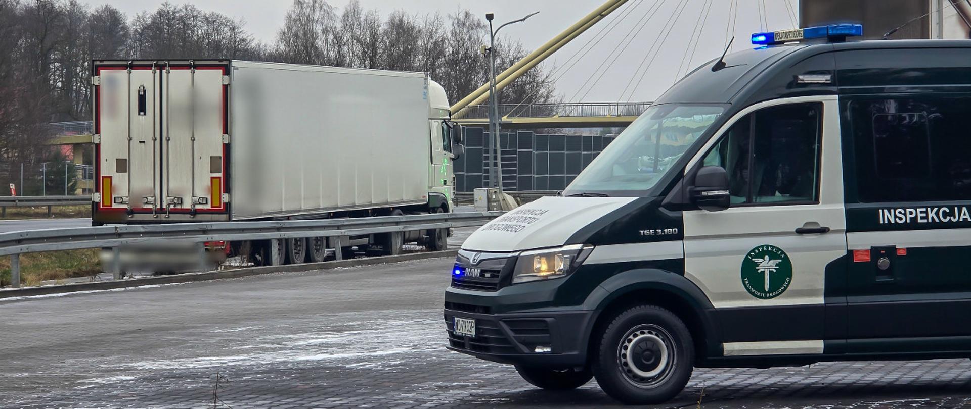 Na pierwszym planie (od prawej): przód oznakowanego furgonu mazowieckiej Inspekcji Transportu Drogowego z włączonymi światłami niebieskimi uprzywilejowania w ruchu drogowym. Pojazd stoi na parkingu MOP Gurba przy drodze ekspresowej S8. W tle: tył zatrzymanego do kontroli tureckiego zespołu pojazdów.