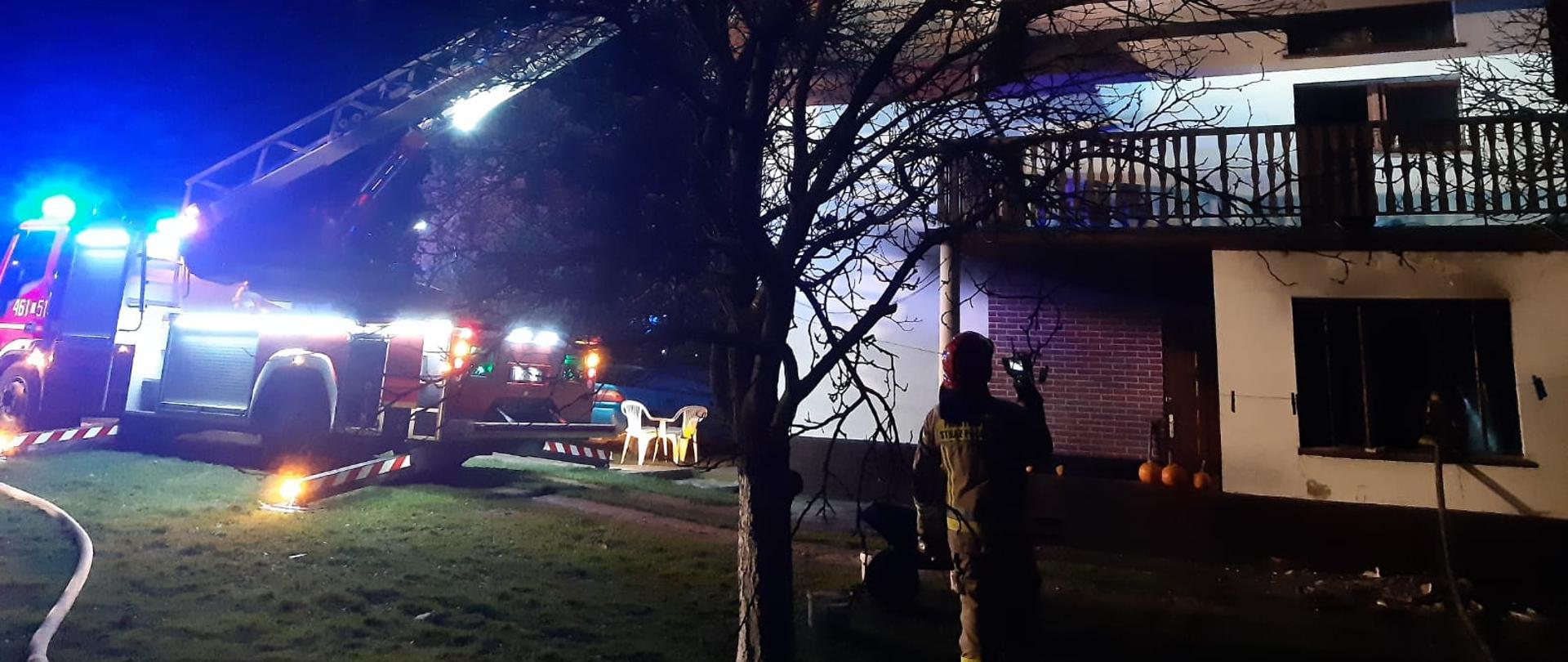 Strażacy gaszą pożar sadzy w przewodzie kominowym z wykorzystaniem drabiny mechanicznej.