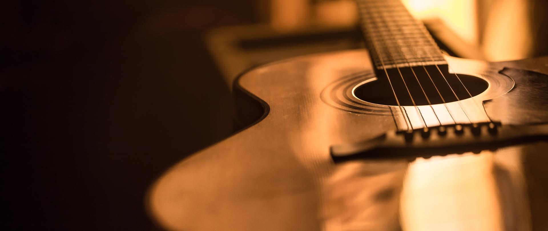 Na zdjęciu zbliżenie gitary akustycznej na pięknym kolorowym tle, koncepcja instrumentów strunowych