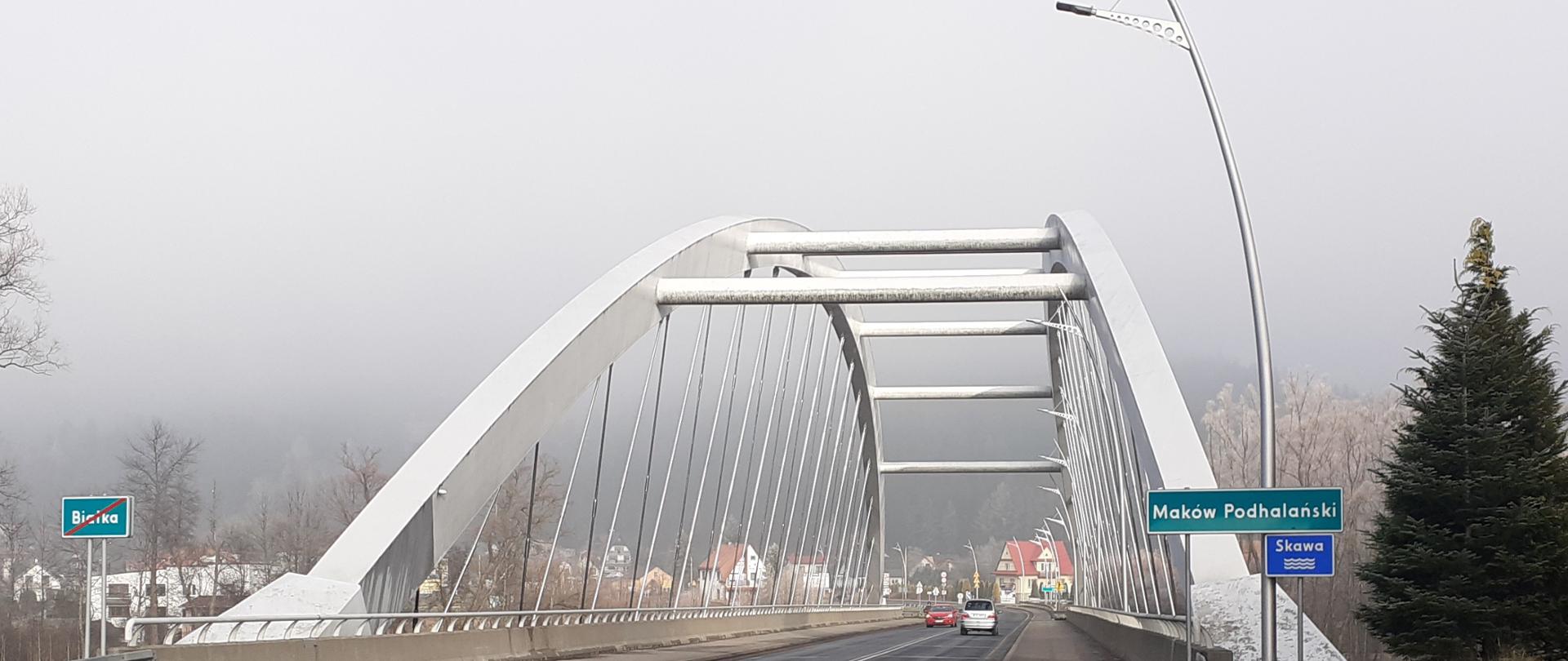 most w Makowie Podhalańskim, po prawej tabliczka z nazwą miasta, po moście jadą samochody