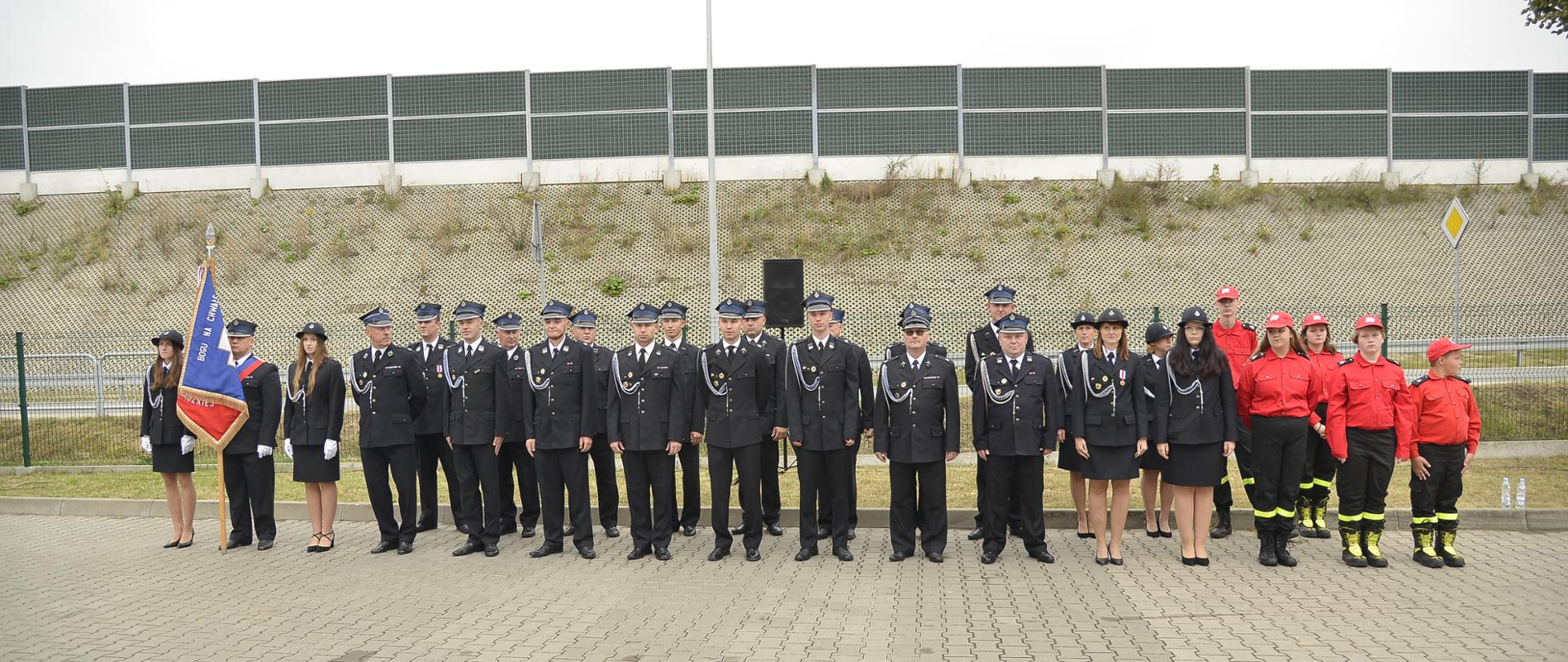 Na zdjęciu w umundurowaniu galowym stojący w dwuszeregu strażacy ratownicy ochotniczej straży pożarnej w otwocku wólce mlądzkiej.