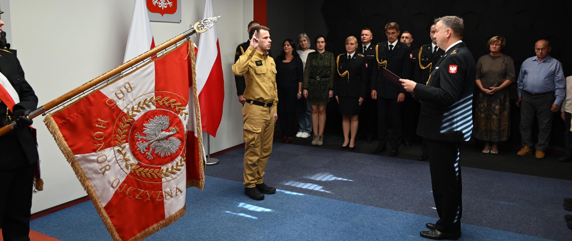 Ślubowanie strażaka Państwowej Straży Pożarnej w obecności pocztu sztandarowego, przełożonego odczytującego rotę oraz zaproszonych gości.