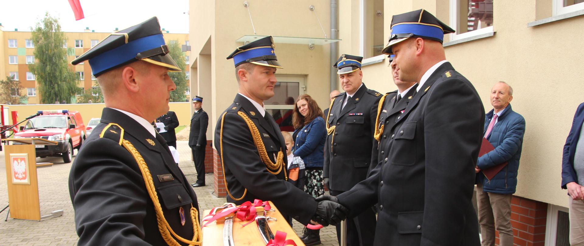 Zdjęcie Przedstawia Komendanta Powiatowego, odbierającego pamiątkowe prezenty od funkcjonariuszy KP PSP Wałcz.