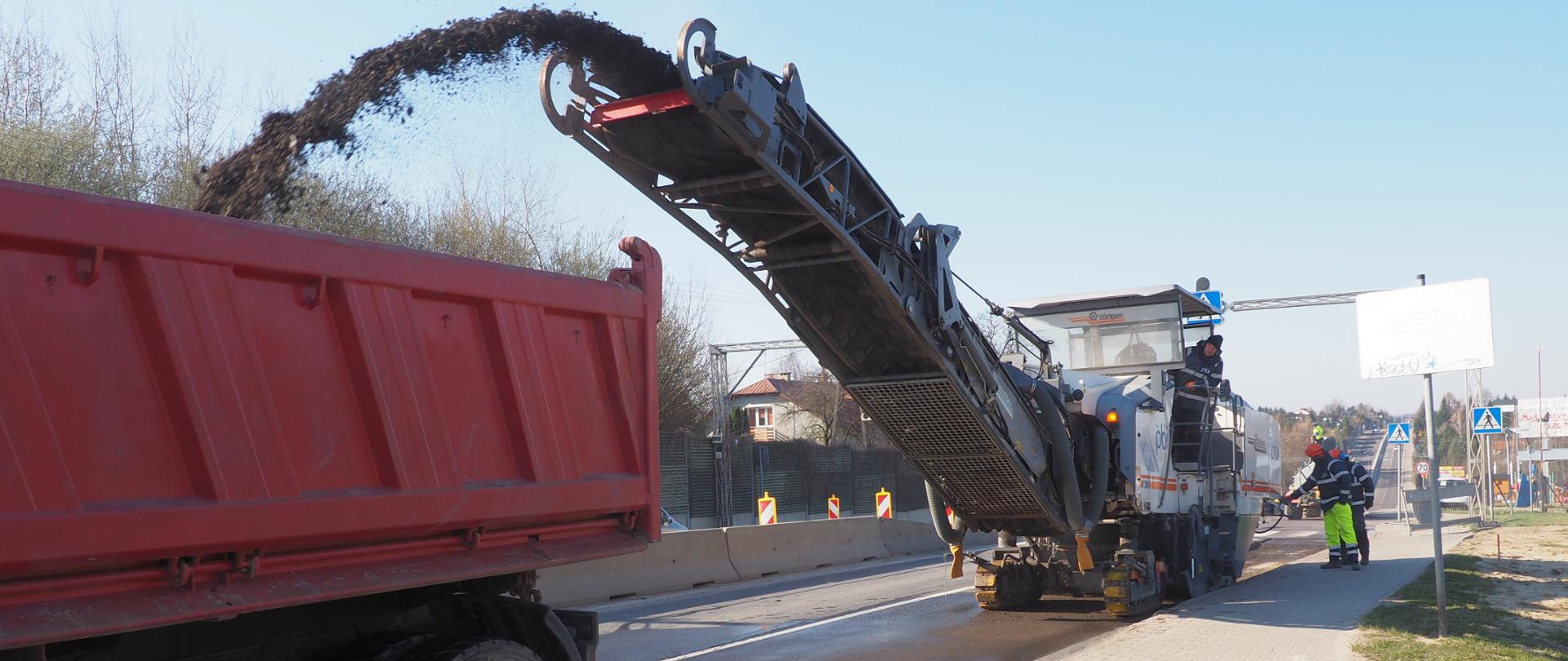 Maszyna ściąga nawierzchnię asfaltową z drogi. Widać pracowników. 