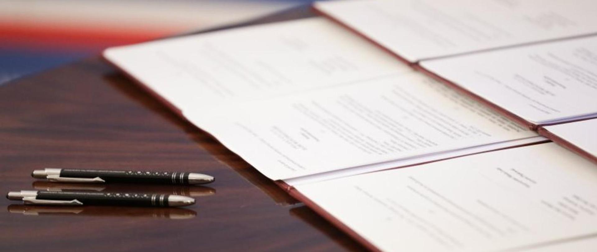 Długopisy na stole oraz otwarte teczki z dokumentami, fot. Danuta Matloch 