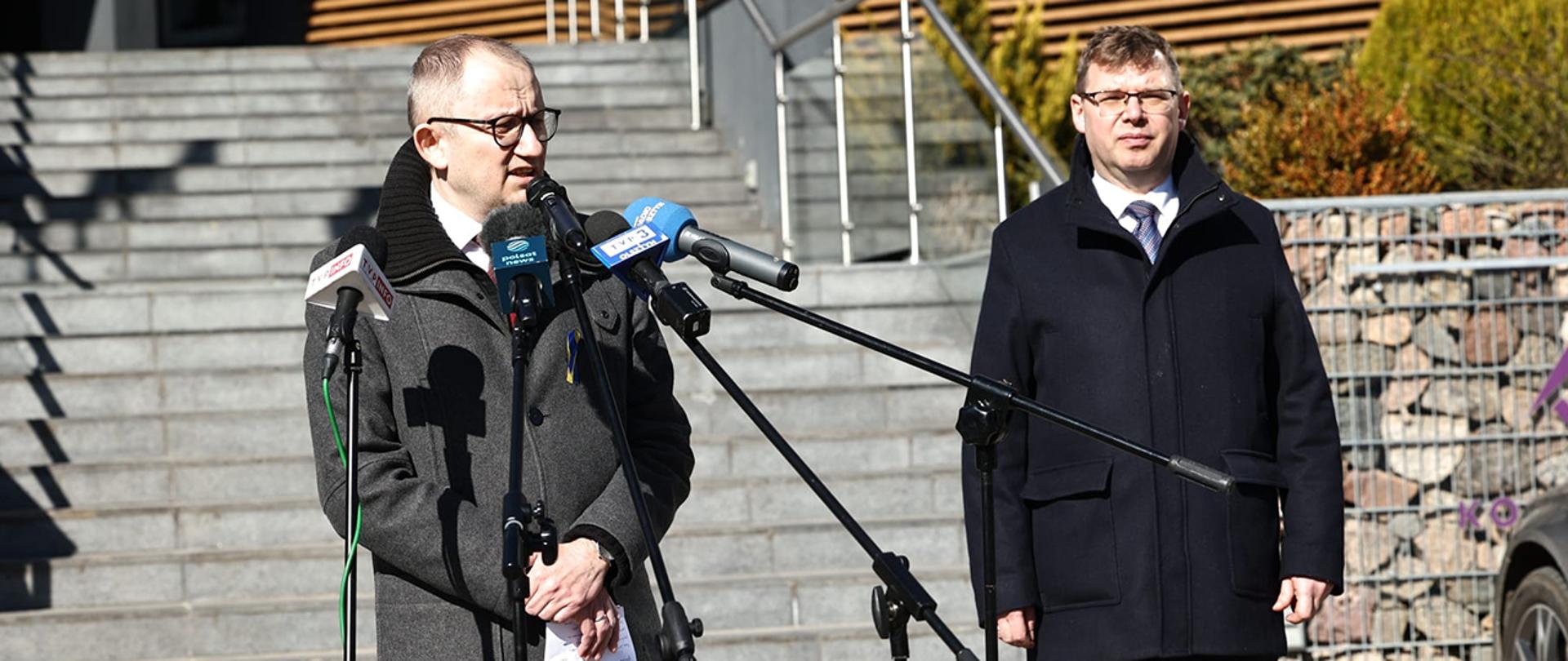 Wiceminister Błażej Poboży przy mikrofonach mediów.