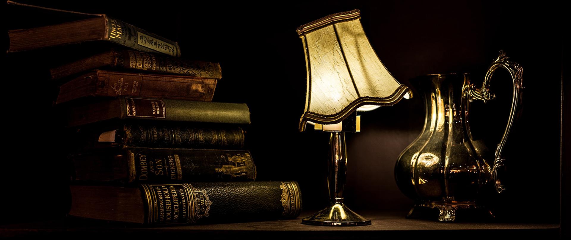 Baner przedstawiający książki, lampę oraz dzban