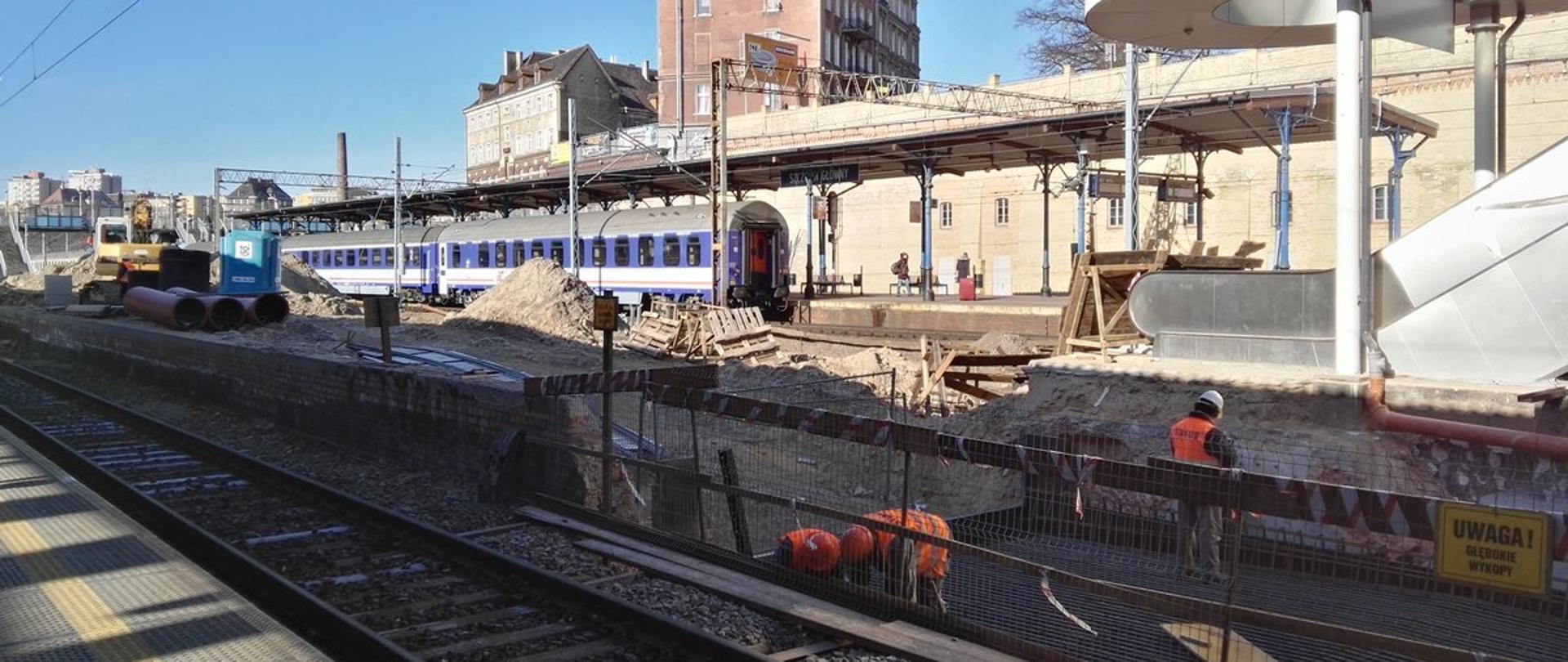 Na zdjęciu widać pracowników na budowie peronu na stacji kolejowej. Po lewej stronie widoczne są maszyny budowlane